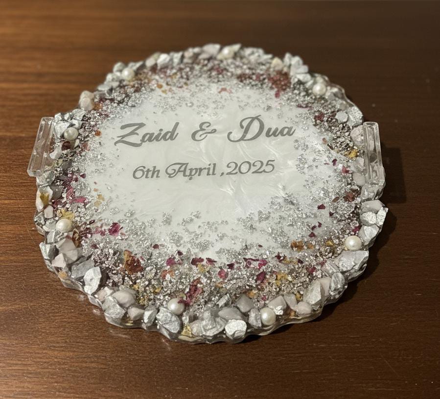 Decorative glass coaster with engraved names and date on a wooden surface
