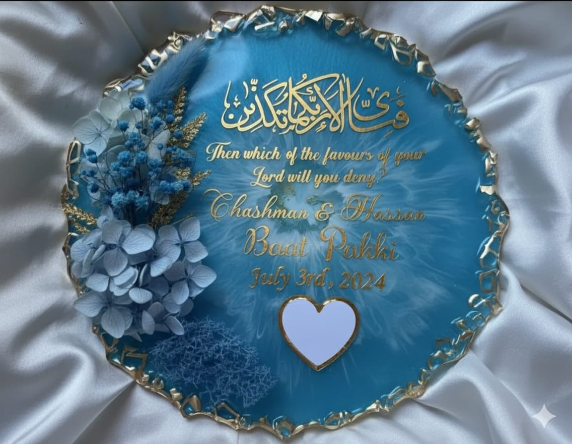 Decorative blue plaque with gold text and floral elements on a white fabric background