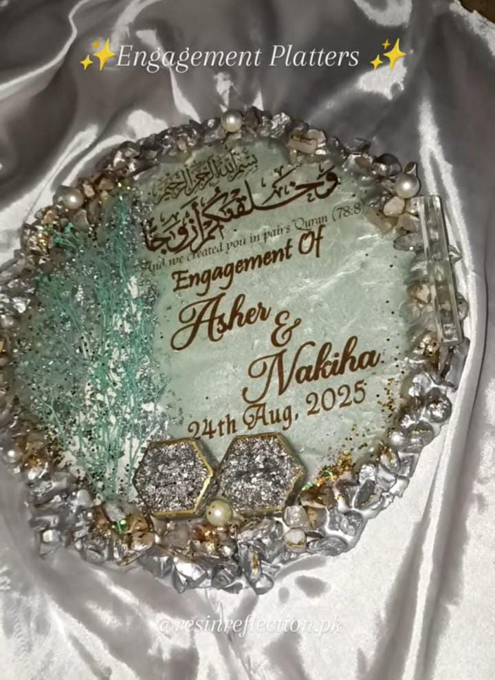 Decorative platter with engraved text for an engagement, featuring pearls and crystals on a white fabric background.