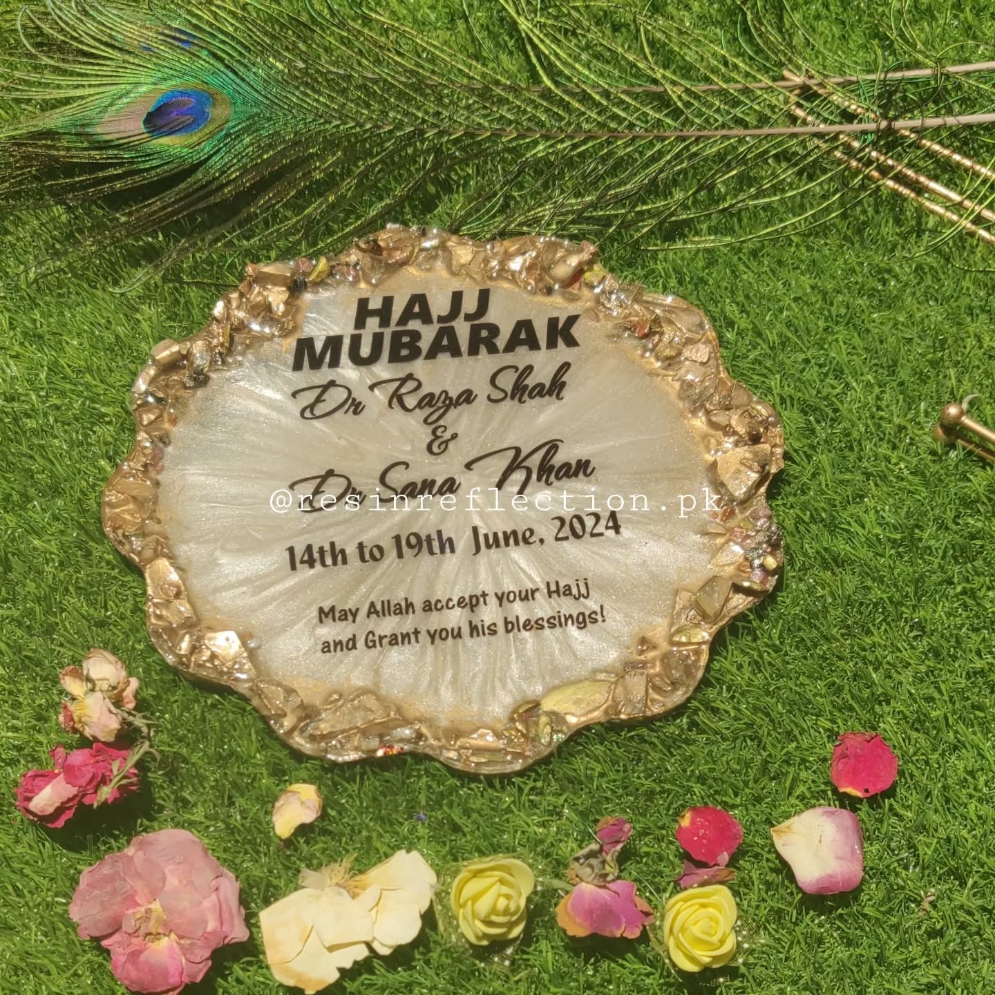 Decorative plate with 'Hajj Mubarak' text on a green background with flowers and peacock feathers.